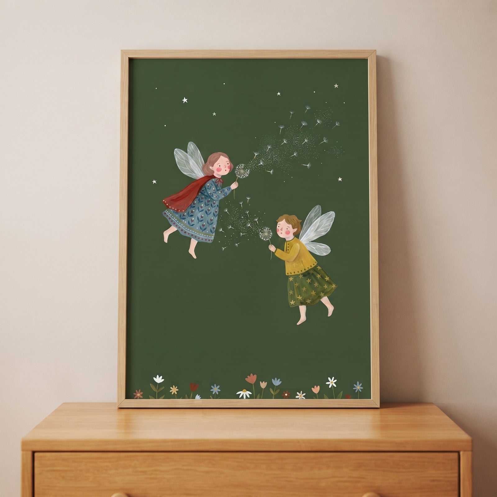 Blowing dandelion seed fairies wall art in a frame shows two winged figures on a green background above a wooden dresser.