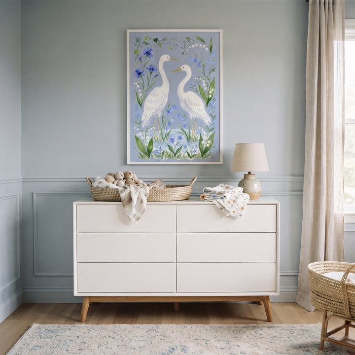 Blue botanical white egret bird wall art above a white dresser in a nursery with light blue walls and neutral decor.