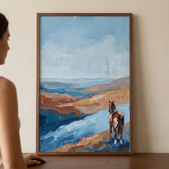 A rectangular artwork in a thin wooden frame hangs on a plain, neutral-toned wall. To the left, a person is partially visible in profile, appearing to gaze at the piece.

