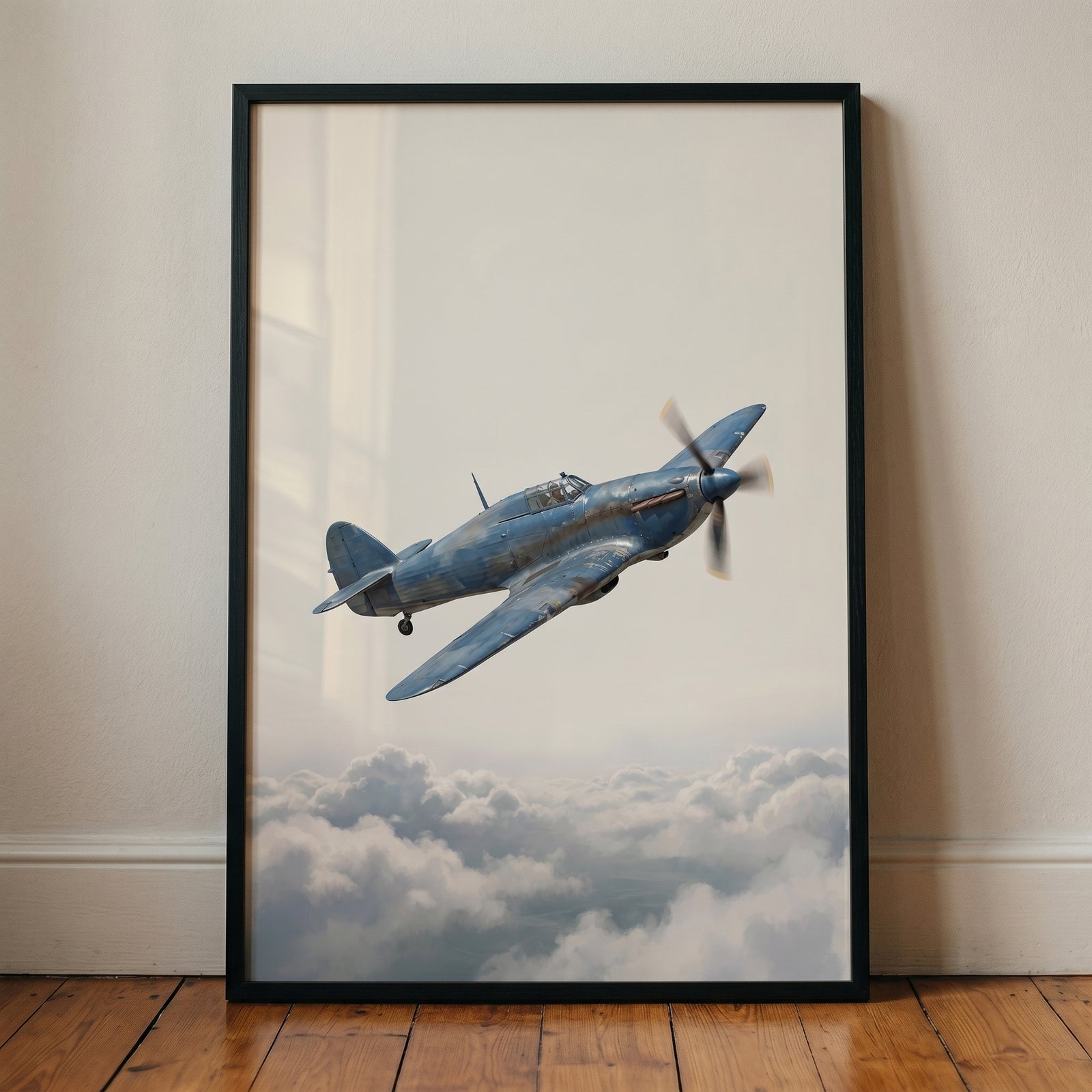 Framed blue fighter airplane wall art of a vintage aircraft flying through a bright sky above soft white clouds.