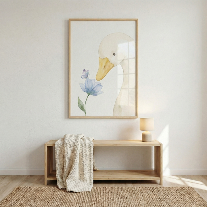 A whimsical watercolor-style illustration of a gentle bird is framed in light wood and hung on a minimalist white wall. The artwork depicts a large, cream-colored goose with a soft yellow beak looking down toward a delicate light blue flower. A small, matching blue butterfly is perched on the flower’s petals. 
