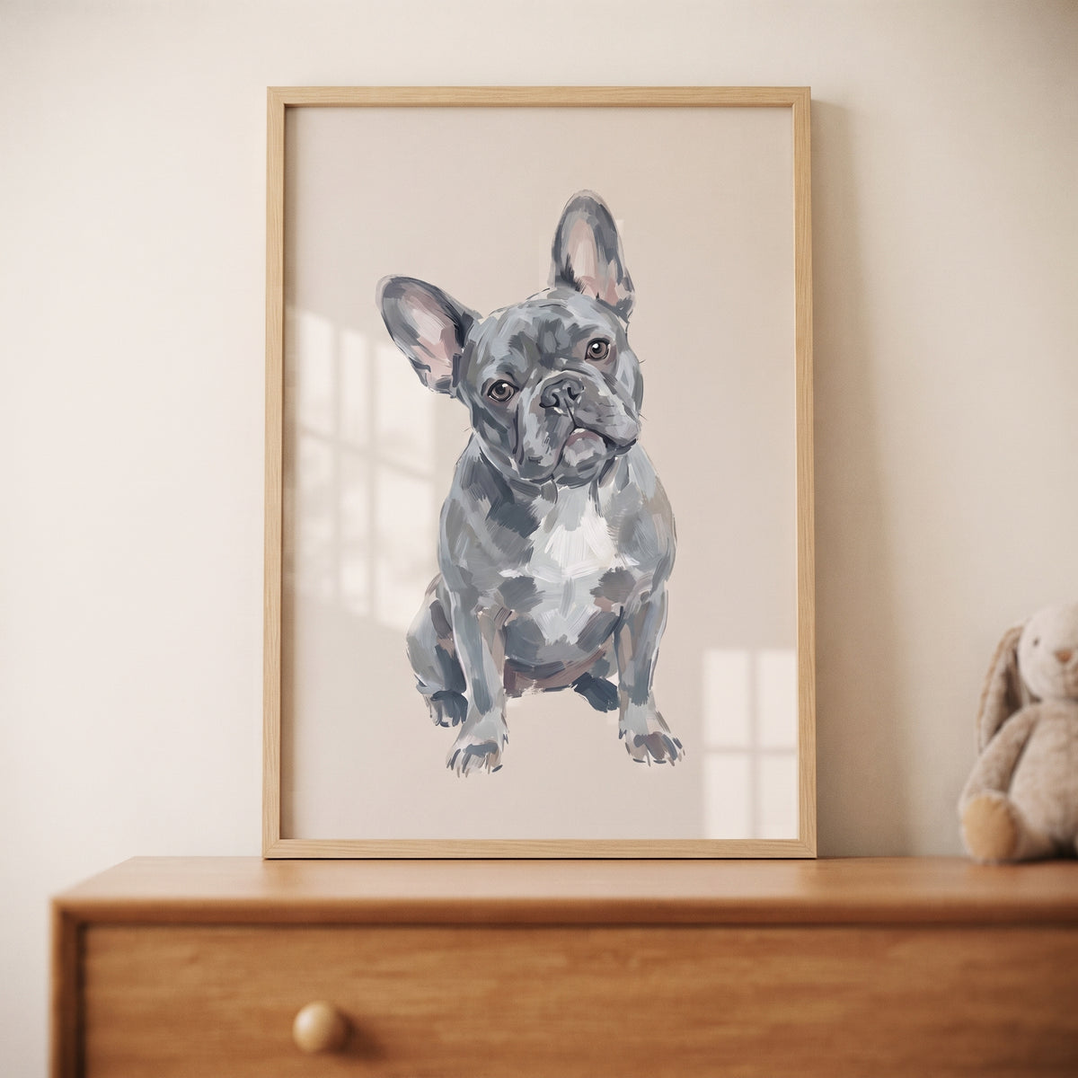 Blue French bulldog wall art in a wooden frame resting on a dresser against a neutral background.