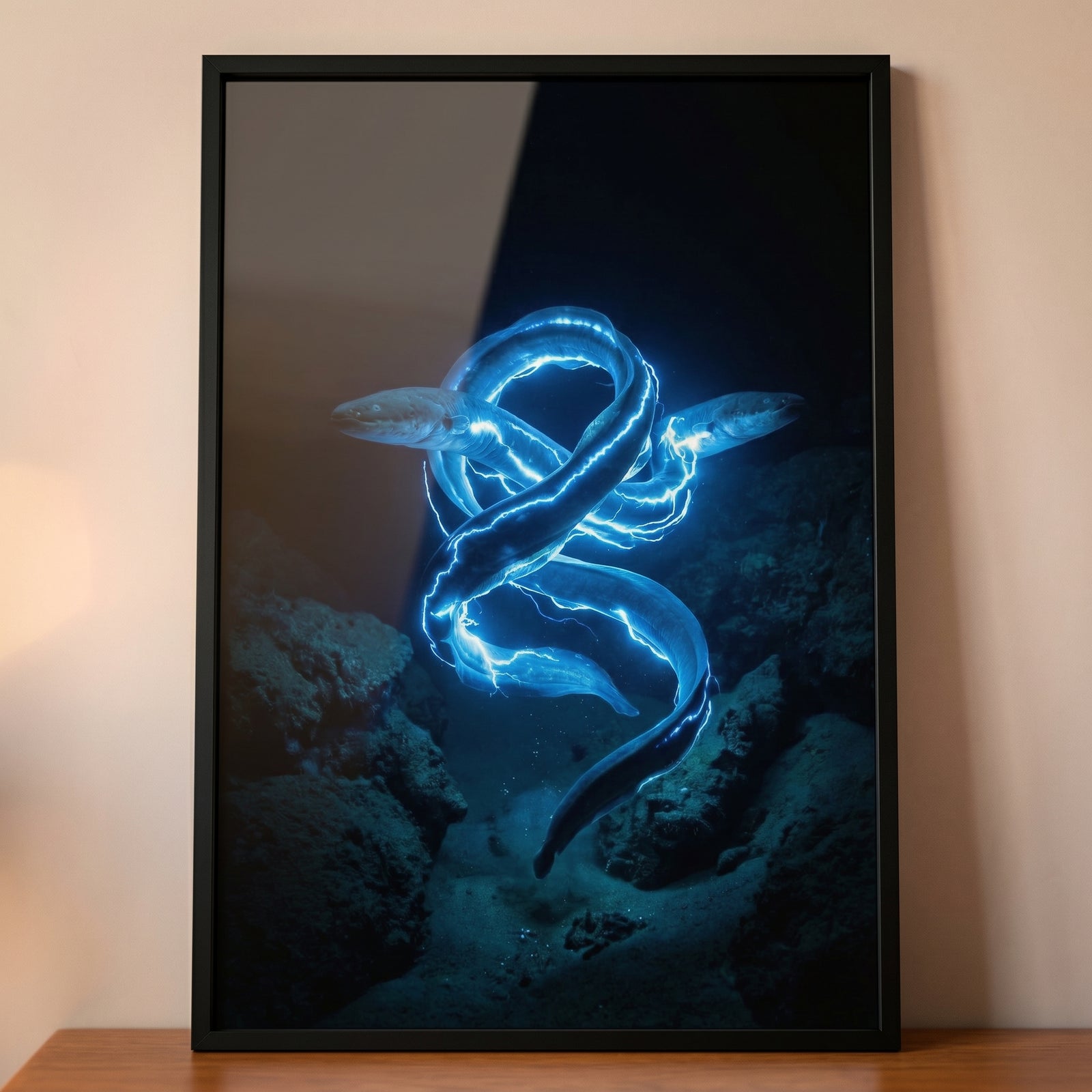 Black framed underwater artwork showing bright blue electric eels swirling together in deep ocean water above a wooden tabletop.