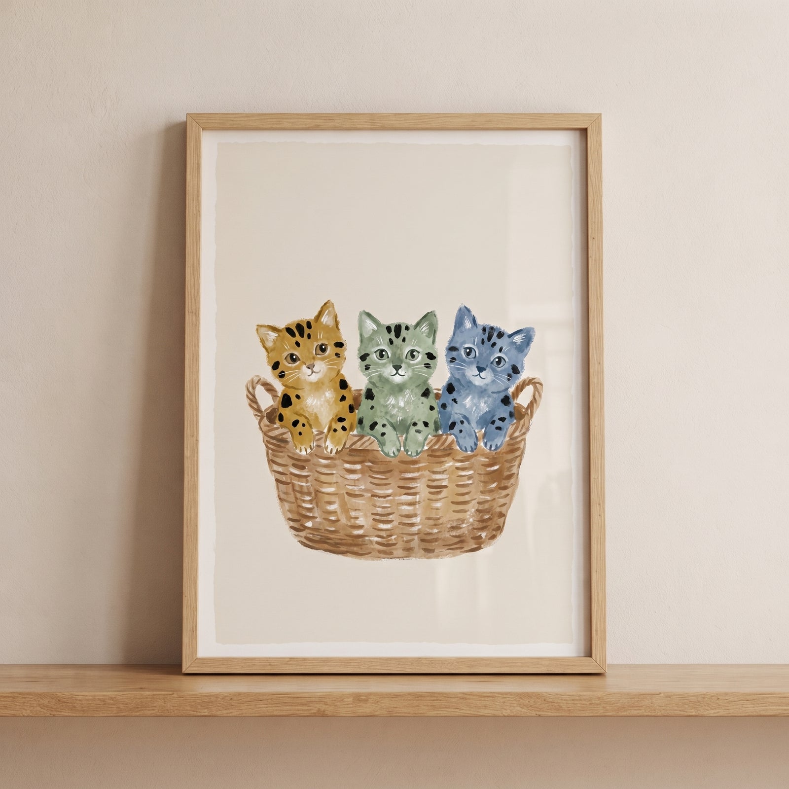 Blue green ochre kittens artwork depicts three spotted cats sitting in a woven basket inside a wooden frame.