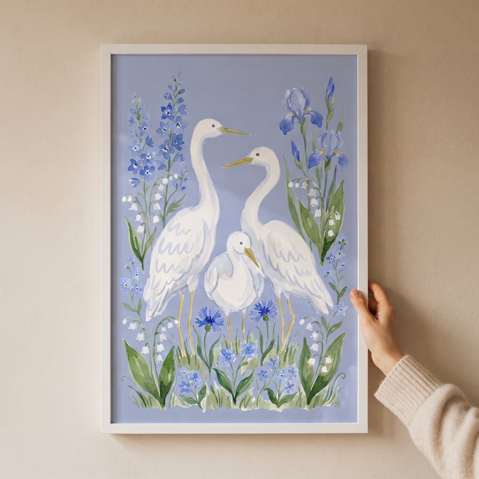 Three white egrets stand among blue flowers and lilies in this blue iris family egret bird wall art.