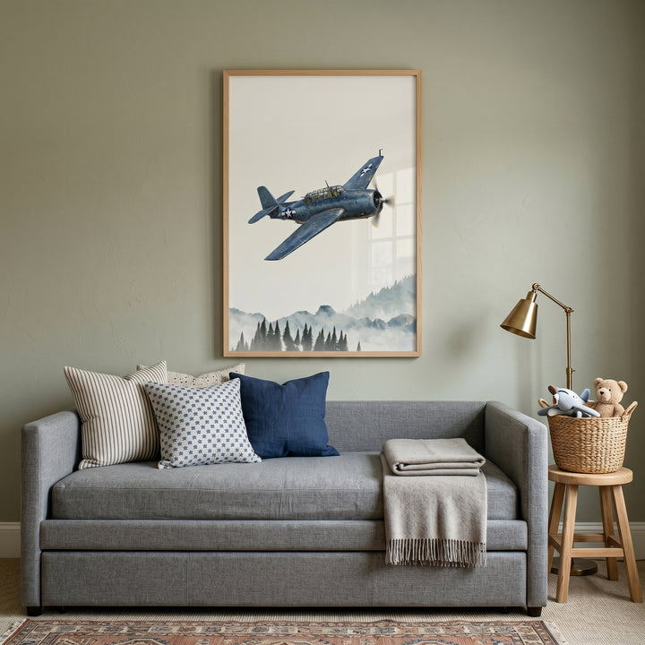 Gray daybed below blue navy propeller airplane wall art in a sage green room with a brass lamp and wooden stool.