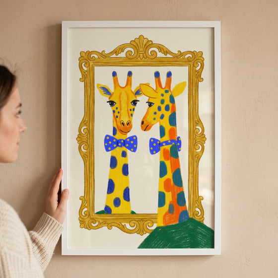 A woman holds framed blue polka dot giraffe wall art of a colorful giraffe wearing a bowtie looking into a gold mirror.