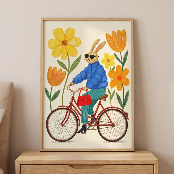 Blue puffer jacket bunny wall art of a rabbit wearing sunglasses and riding a red bicycle among large colorful flowers.