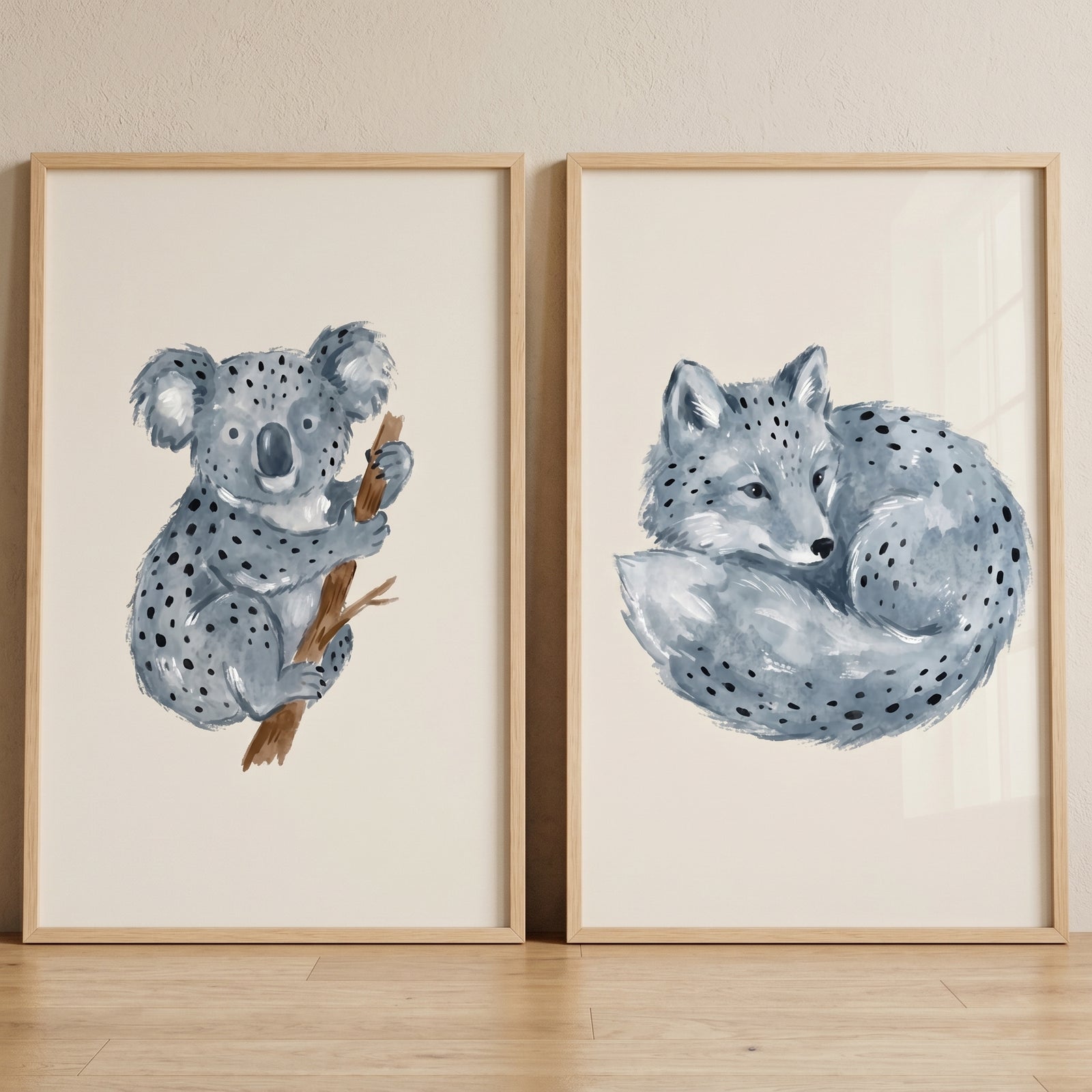 Blue spotted watercolor animals wall art set of 2 featuring a koala on a branch and a curled fox in light wood frames.