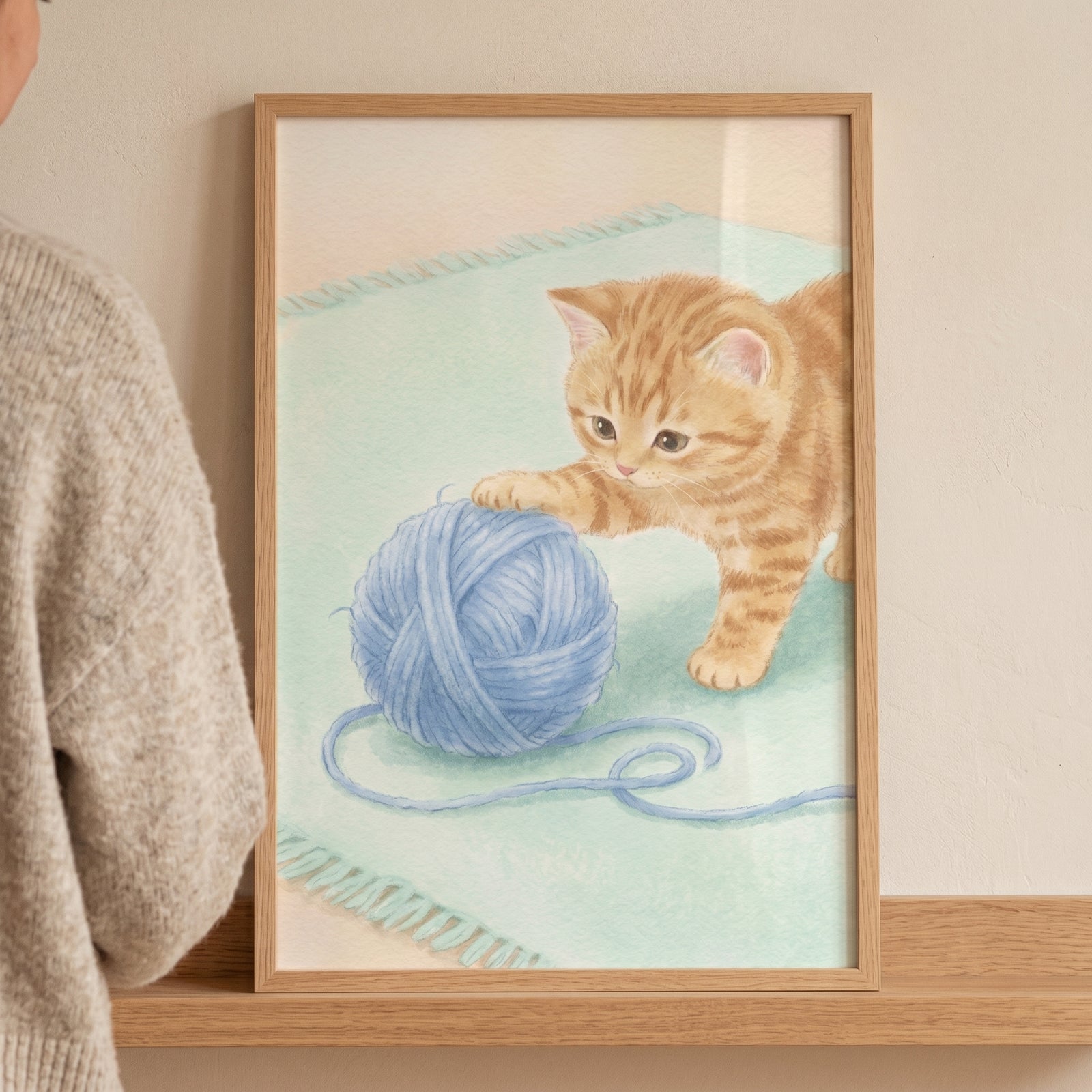 Orange tabby kitten playing with a blue ball of yarn on a light green rug in this blue yarn ball kitten artwork.