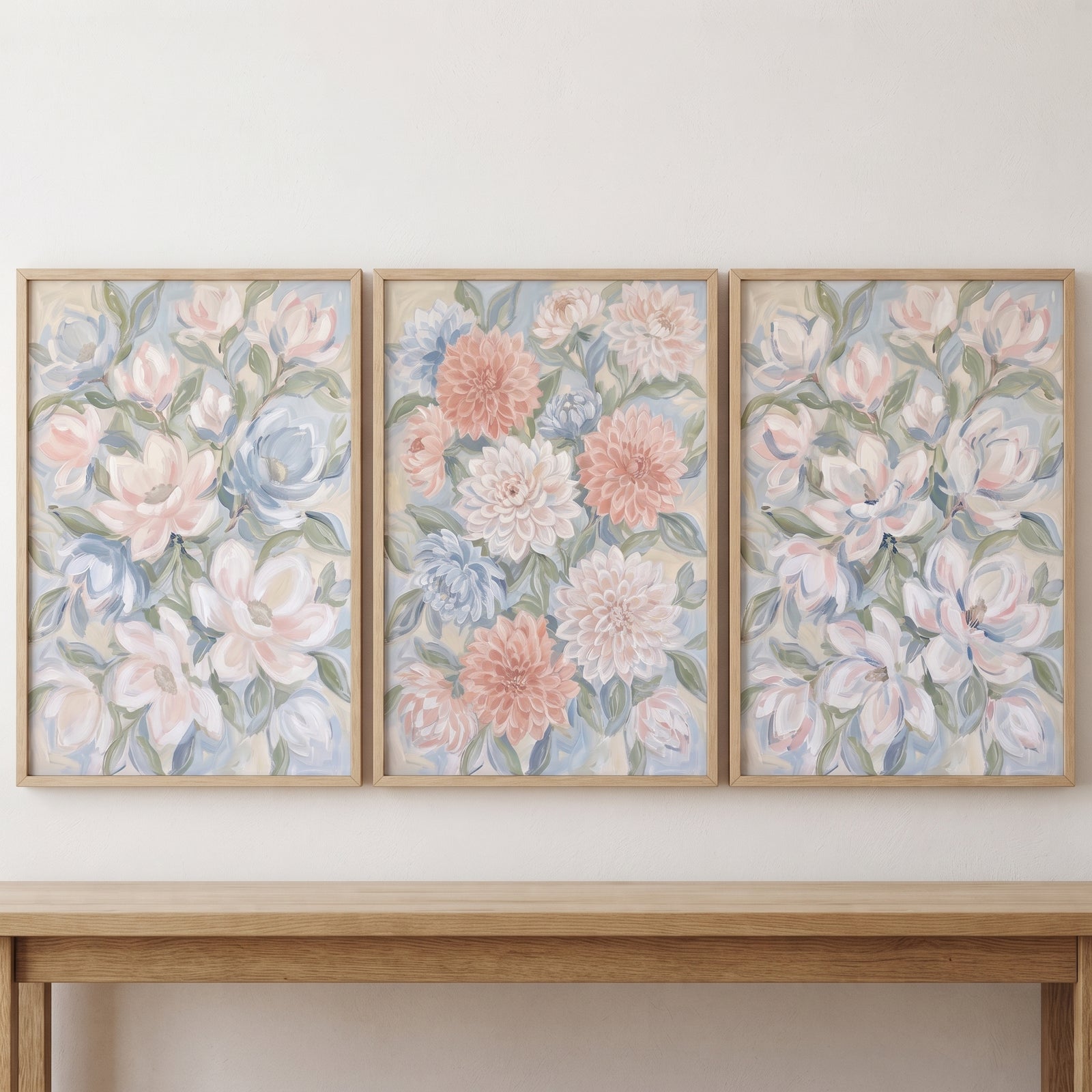 Framed blush blue garden floral wall art set of 3 featuring soft pink and blue flowers above a light wood table.