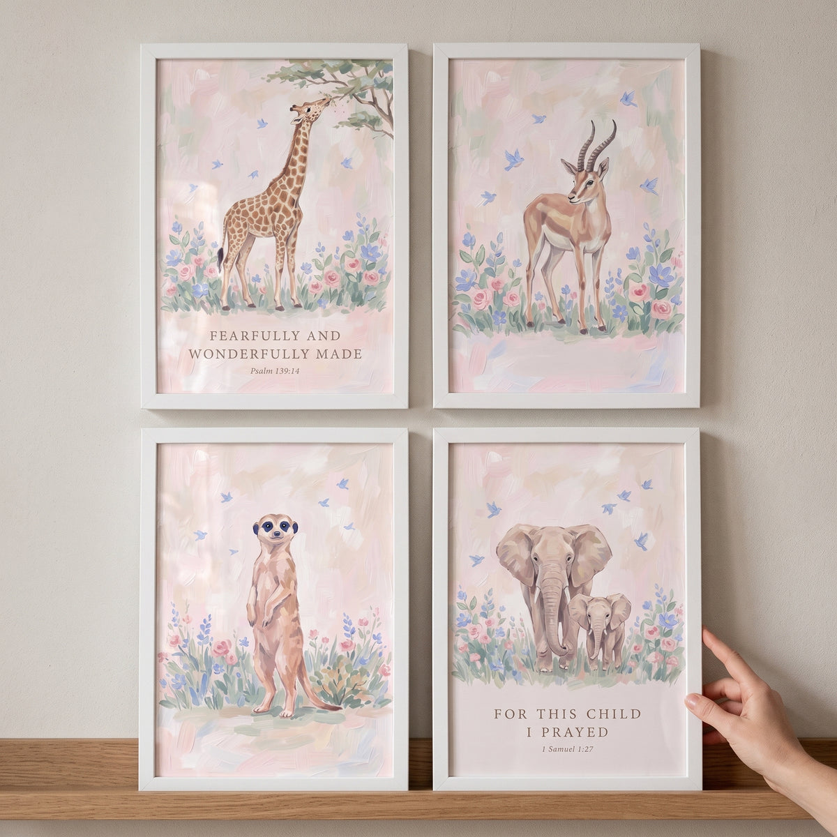 Blush botanical safari animals wall art set of 4 with a giraffe, gazelle, meerkat, and elephants in white frames.