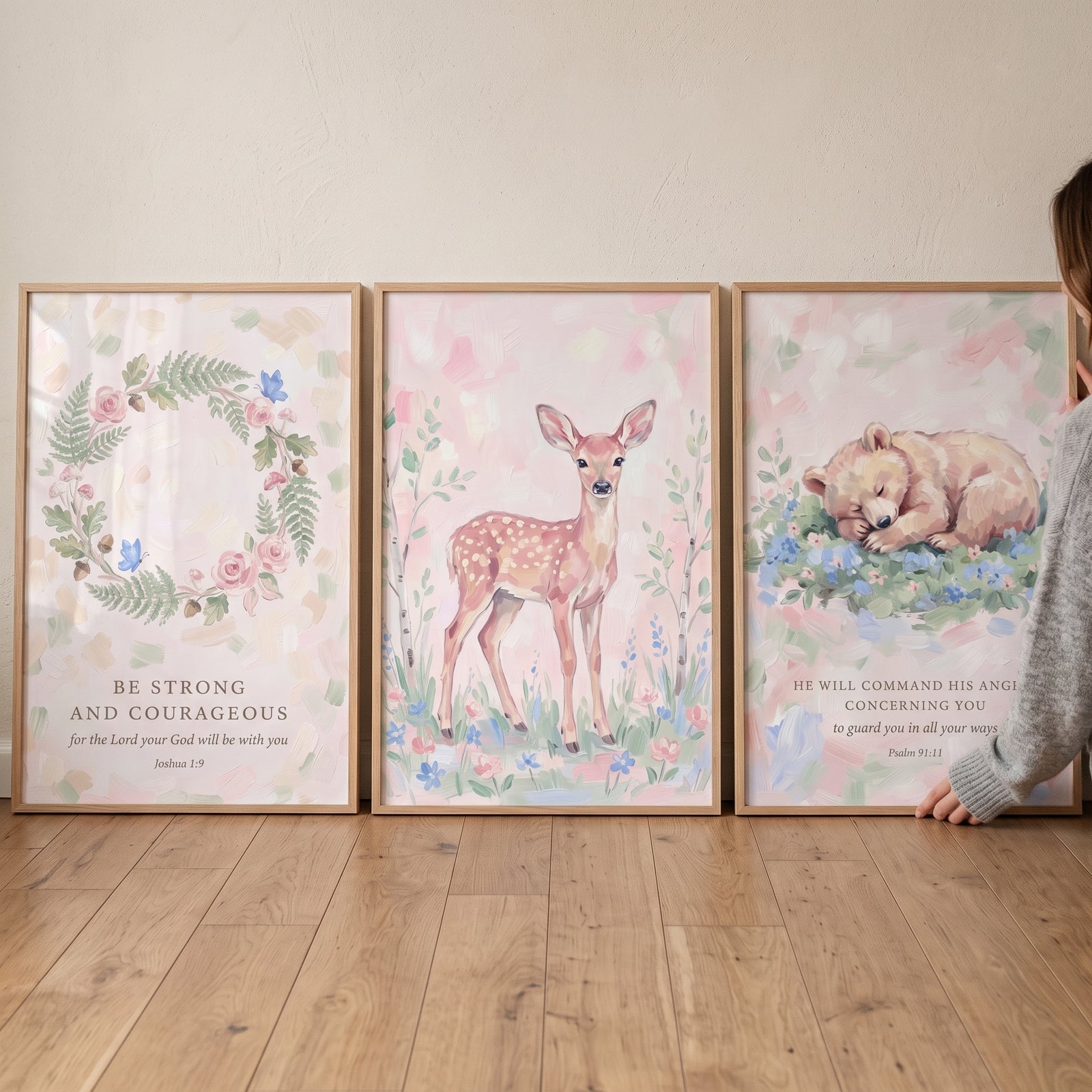 Blush pink floral scripture bible wall art set of 3 with a wreath, a spotted fawn, and a sleeping bear cub on wood floor.