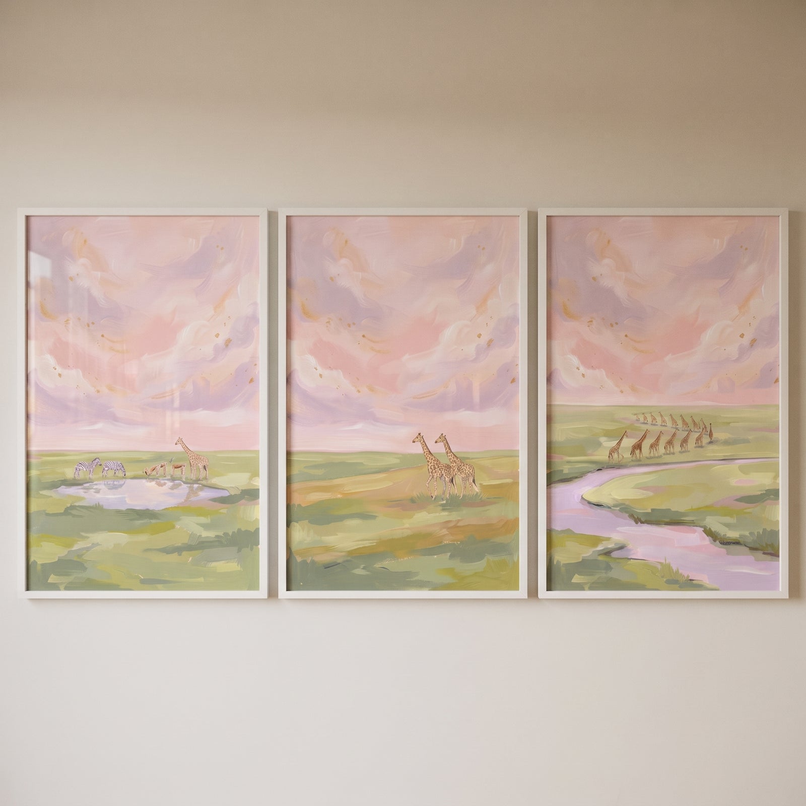 Blush pink savanna giraffe wall art set of 3 depicts animals by a watering hole and river under a soft pink sky.