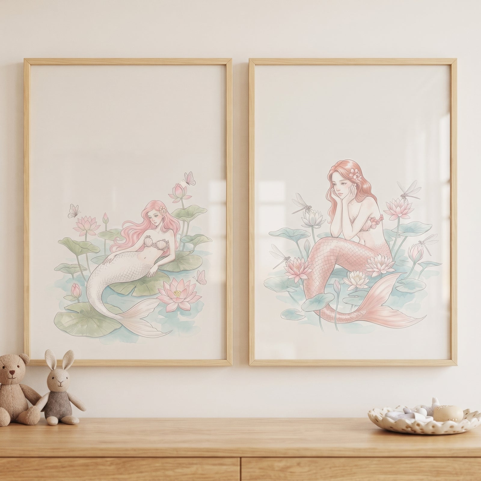 Blush pink watercolor mermaid wall art set of 2 with lotuses hung above a wooden dresser with plush toys.