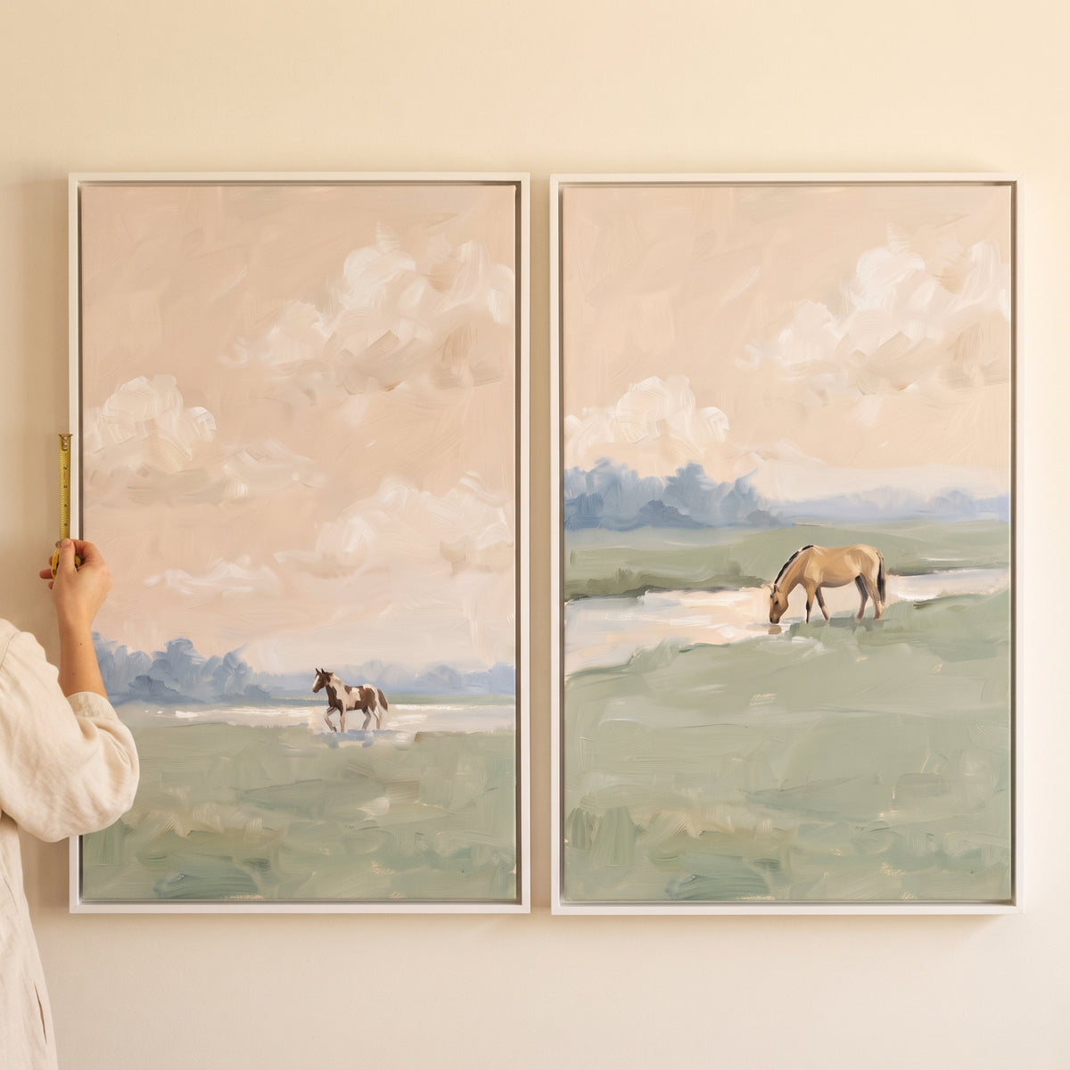 Blush sky impressionist horse wall art set of 2 in white frames with scenes of horses in soft green and tan landscapes.