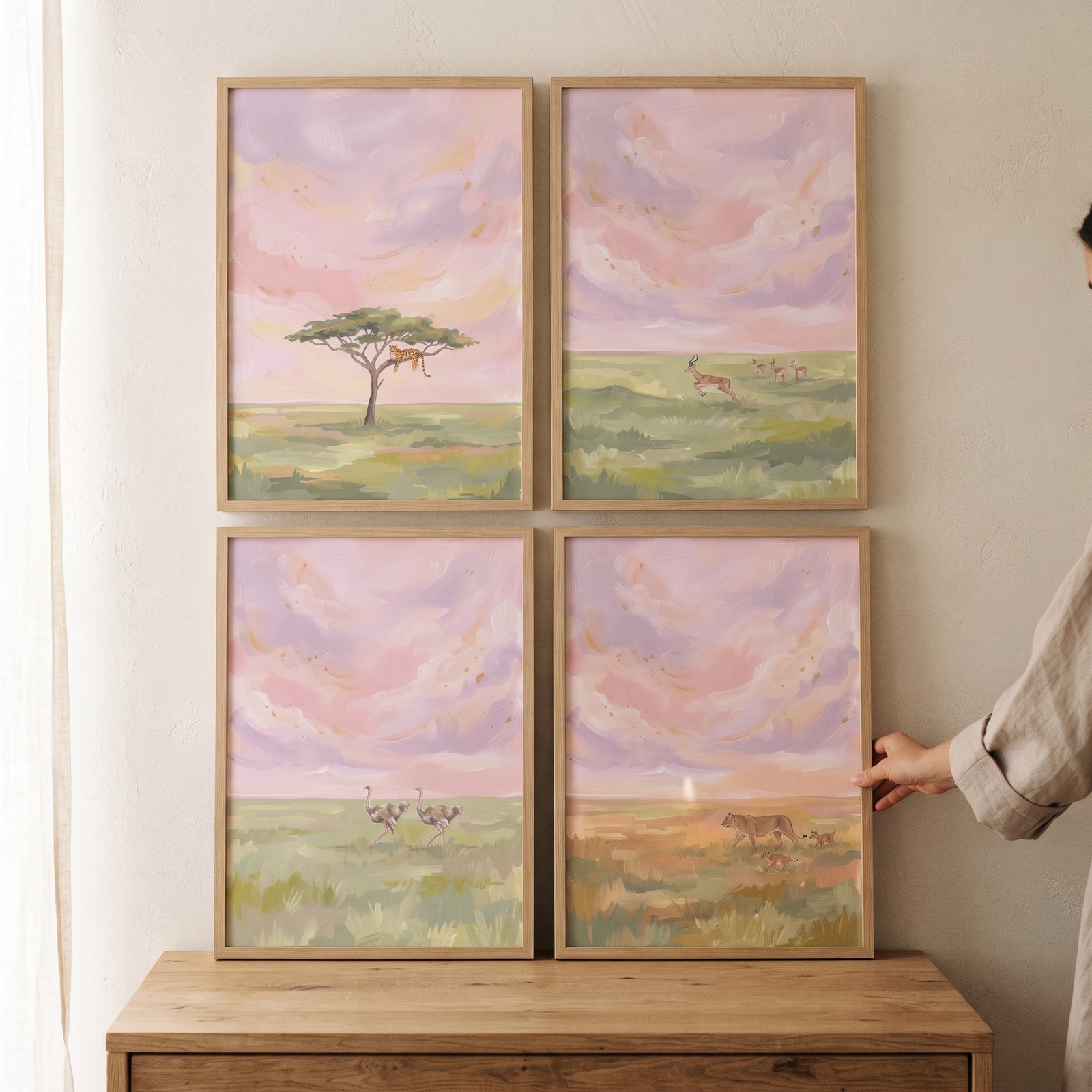 Blush sunset safari animals wall art set of 4 in wooden frames featuring lions, cheetah, and ostriches on a dresser.