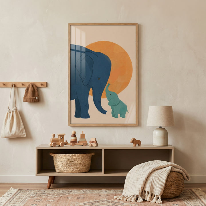 Framed illustration of a large blue elephant gently touching trunks with a smaller green elephant set against a warm orange circle, displayed above a wooden bench with toys and a woven basket. The artwork adds a soft and nurturing focal point to a neutral toned nursery with cozy textures and simple decor.