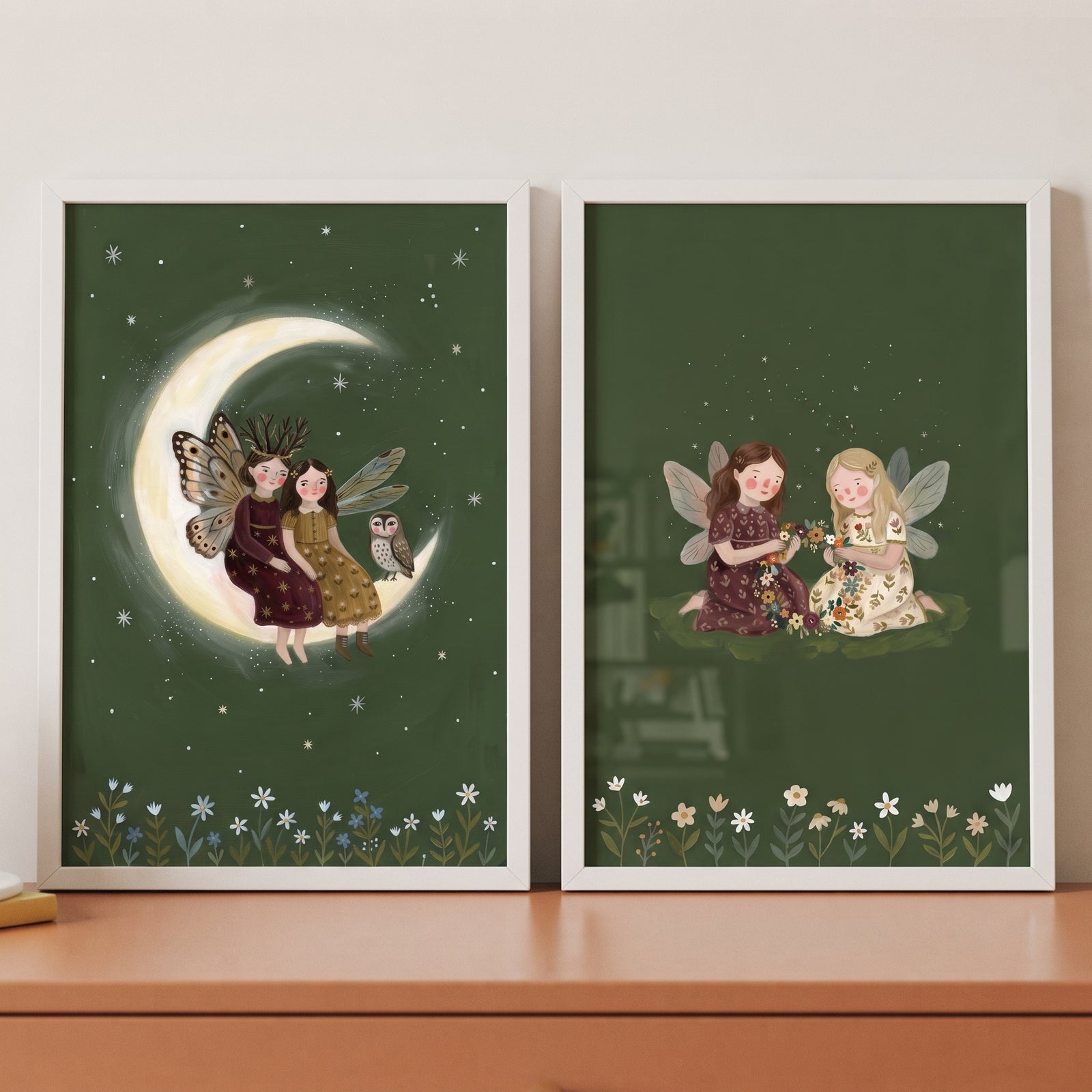 Botanical dark green fairies wall art set of 2 shows whimsical winged figures on a crescent moon and in a floral meadow.