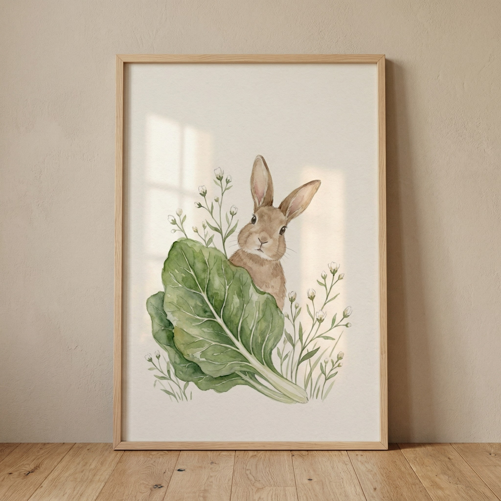 A vertical wooden frame leans against a neutral beige wall on a light wood floor. The artwork inside features a watercolor-style illustration of a small brown rabbit peeking out from behind a large, textured green leaf with white veins. Sprigs of tiny white wildflowers with green stems surround the rabbit and leaf on a cream background. Soft window light creates gentle shadows across the art piece, giving it a calm and natural feel.