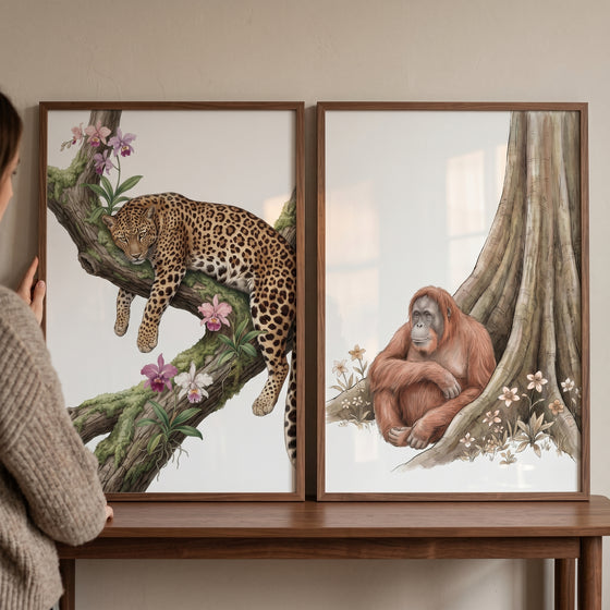 Botanical jungle animal wall art set of 2 with a leopard on a branch and an orangutan sitting by a large tree.
