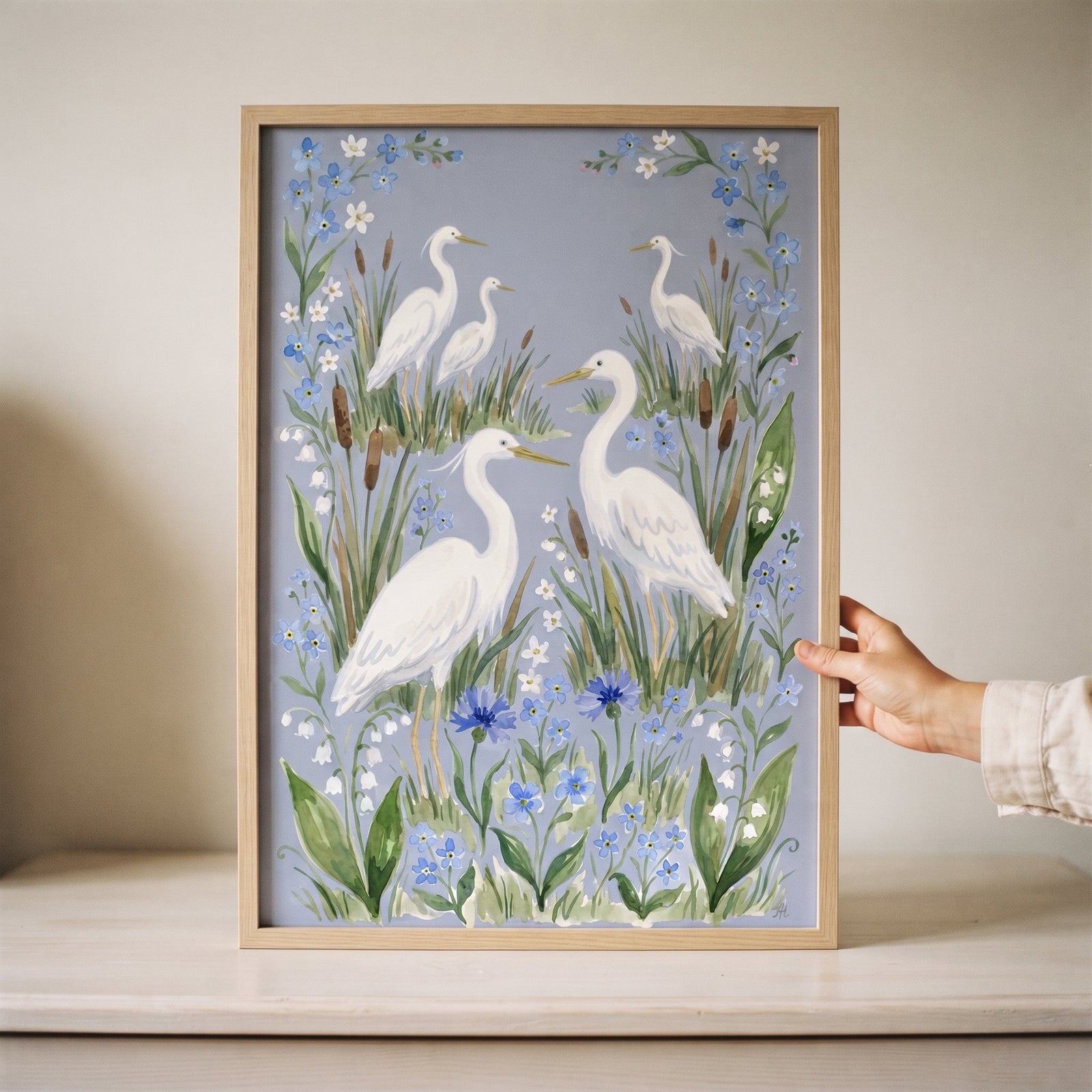 Botanical marsh white heron bird wall art featuring white herons and blue flowers inside a light wood frame.