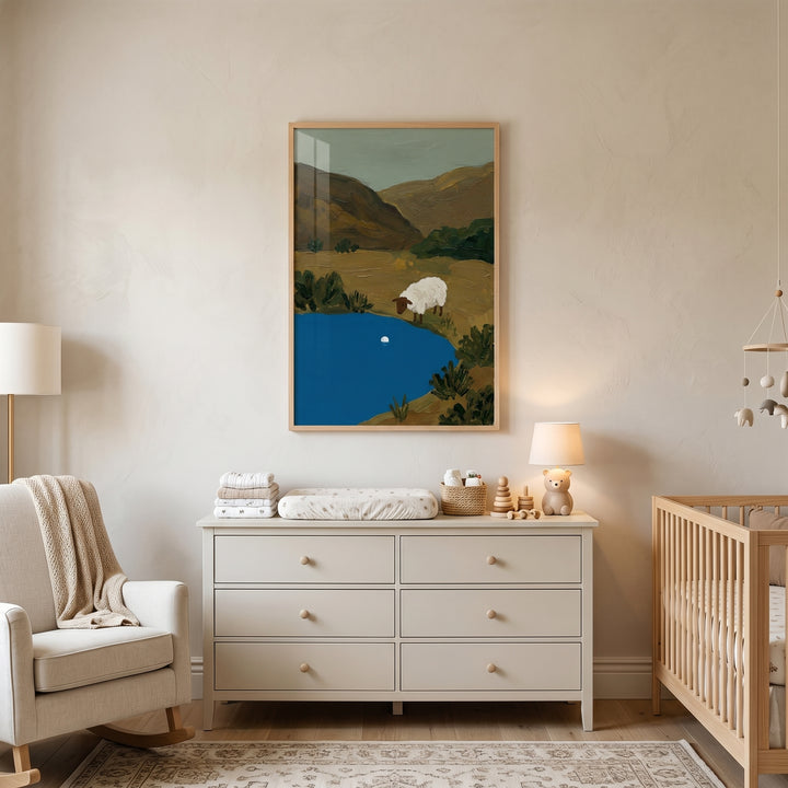 A nursery features brown face water sheep wall art above a beige dresser, with a rocking chair and wooden crib.