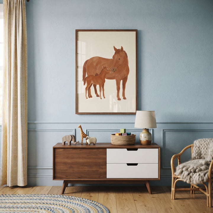 Brown mother baby horse wall art hangs over a wood sideboard in a blue room with a wicker chair and a round rug.