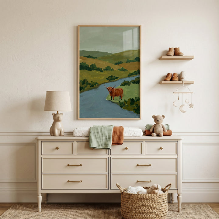 Brown shaggy highland cow wall art above a cream dresser with a bear lamp, teddy bear, and wooden wall shelves.