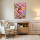 A serene and well-lit nursery or child's room features neutral-toned walls with decorative molding. Centered on the wall is a framed piece of artwork depicting a lively brown squirrel leaping between tree branches. The artwork's background is a vibrant pink, filled with stylized flowers in shades of purple, yellow, and blue.
