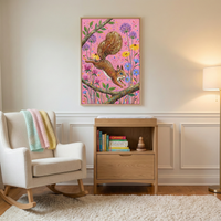 A serene and well-lit nursery or child's room features neutral-toned walls with decorative molding. Centered on the wall is a framed piece of artwork depicting a lively brown squirrel leaping between tree branches. The artwork's background is a vibrant pink, filled with stylized flowers in shades of purple, yellow, and blue.
