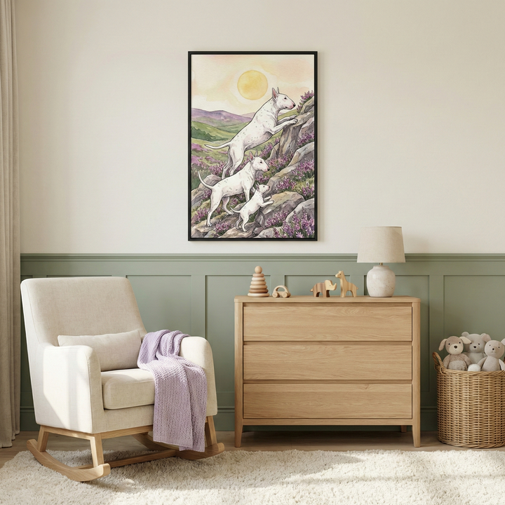 A cozy nursery room with two-toned walls in cream and sage green. Centered on the wall is a black-framed illustration of three white dogs with unique profiles climbing a rocky hillside dotted with purple flowers under a large, soft yellow sun. Below the art sits a light-wood three-drawer dresser with wooden toys and a small lamp on top. To the left is a cream-colored rocking chair draped with a light purple knit blanket. 