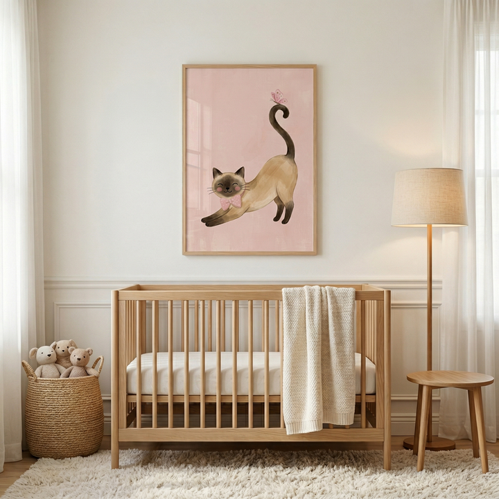 A serene, minimalist nursery room features neutral tones. A light wood-framed illustration on a pink background shows a cute, slender beige and brown cat in a playful stretch. The cat wears a small pink bow, and a pink butterfly sits on its tail. Below, a light wooden crib holds a white mattress and a cream-colored blanket. To the left is a woven basket with three plush teddy bears. To the right stands a floor lamp with a beige shade and a small wooden stool on a white shag rug.