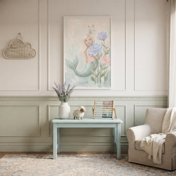 Butterfly topped blonde mermaid wall art above a light blue table with an abacus and plush sheep in a neutral nursery.