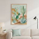 Modern living room with a light beige sofa. A large watercolor painting of desert cacti and agave in soft greens, blues, and browns, framed in natural wood, hangs centered above the sofa.