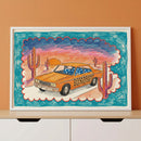 Colorful framed artwork of a stylized orange car with leopard print doors and blue star-patterned windows, parked in a cartoonish desert landscape with cacti and a vivid sunset sky. The scene is surrounded by a bold blue and red scalloped border.