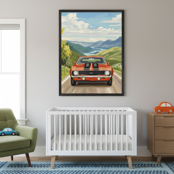 Vibrant car artwork showing a retro orange sports car centered on a road flanked by wildflowers and mountain views, framed above a white crib. The nursery features toy cars, a green armchair, and soft grey walls with natural light from a nearby window.