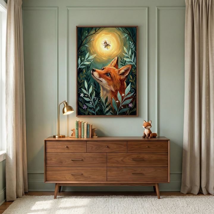 A calm, modern nursery or bedroom with sage green walls and a wooden dresser, featuring a framed woodland illustration of a fox gazing up at a glowing crowned bee, styled with soft curtains, books, a small fox figurine, and warm, natural light.