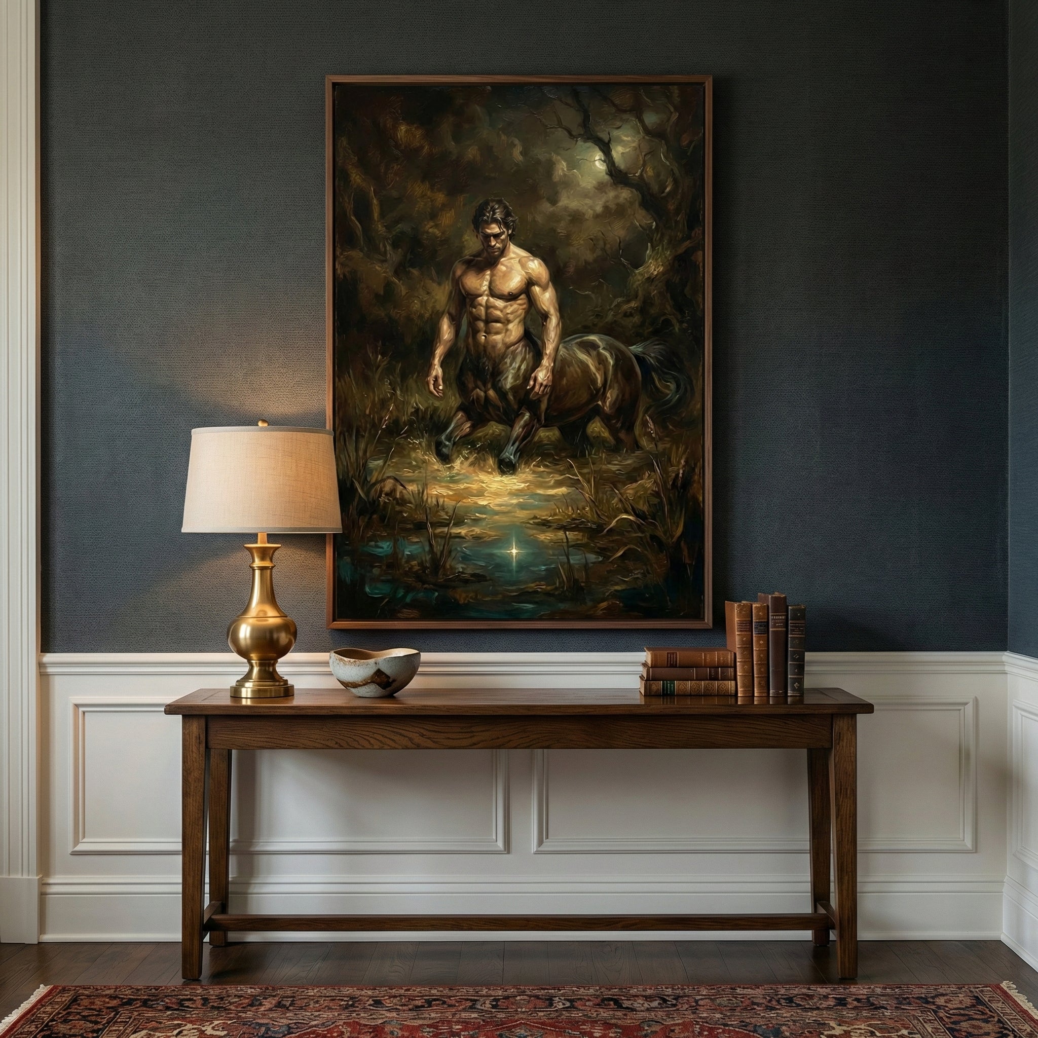 Framed painting of a centaur in a dimly lit enchanted forest, hung above a wooden console table in a traditional interior setting with classic decor, including a brass lamp, stacked books, and a ceramic bowl.