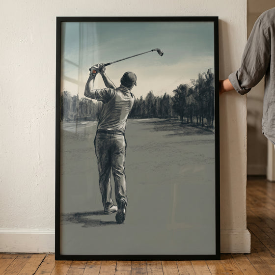 Framed charcoal swing golfer sports wall art depicts a man finishing his golf swing on a treelined course.