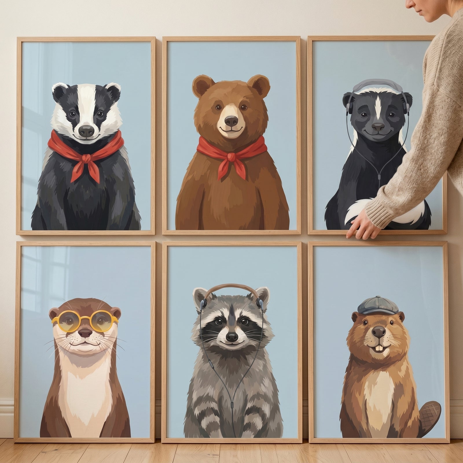A person hangs a cheerful blue forest animals wall art set of 6 featuring a badger, bear, skunk, otter, raccoon, and beaver.