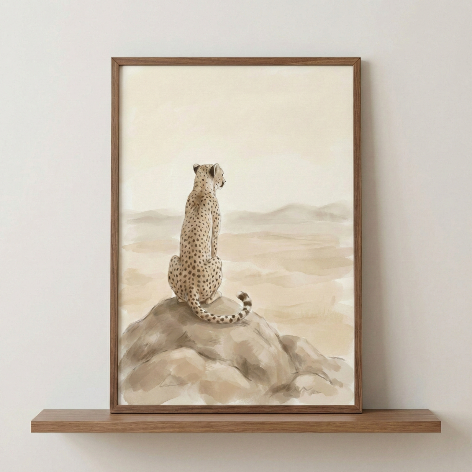 An earthy-toned framed artwork depicts a cheetah sitting on a large rock, looking out over a vast, minimalist desert landscape. The animal is shown from behind, its spotted coat and long, curved tail rendered in warm browns and tans against a hazy, atmospheric background of soft, rolling hills. 

