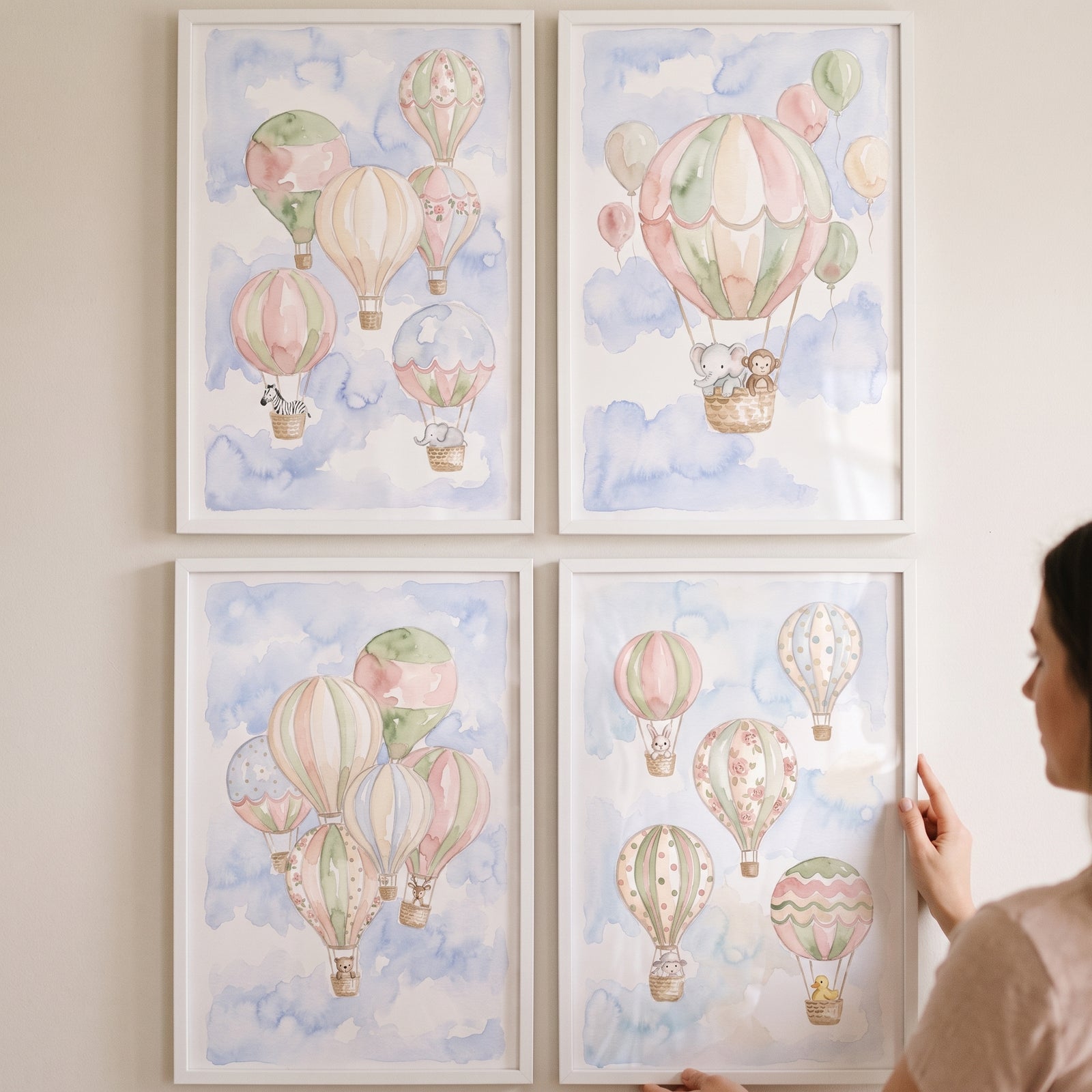 Chic blush hot air balloon artwork set of 4 featuring soft pastel colors and cute animals displayed in frames on a wall.