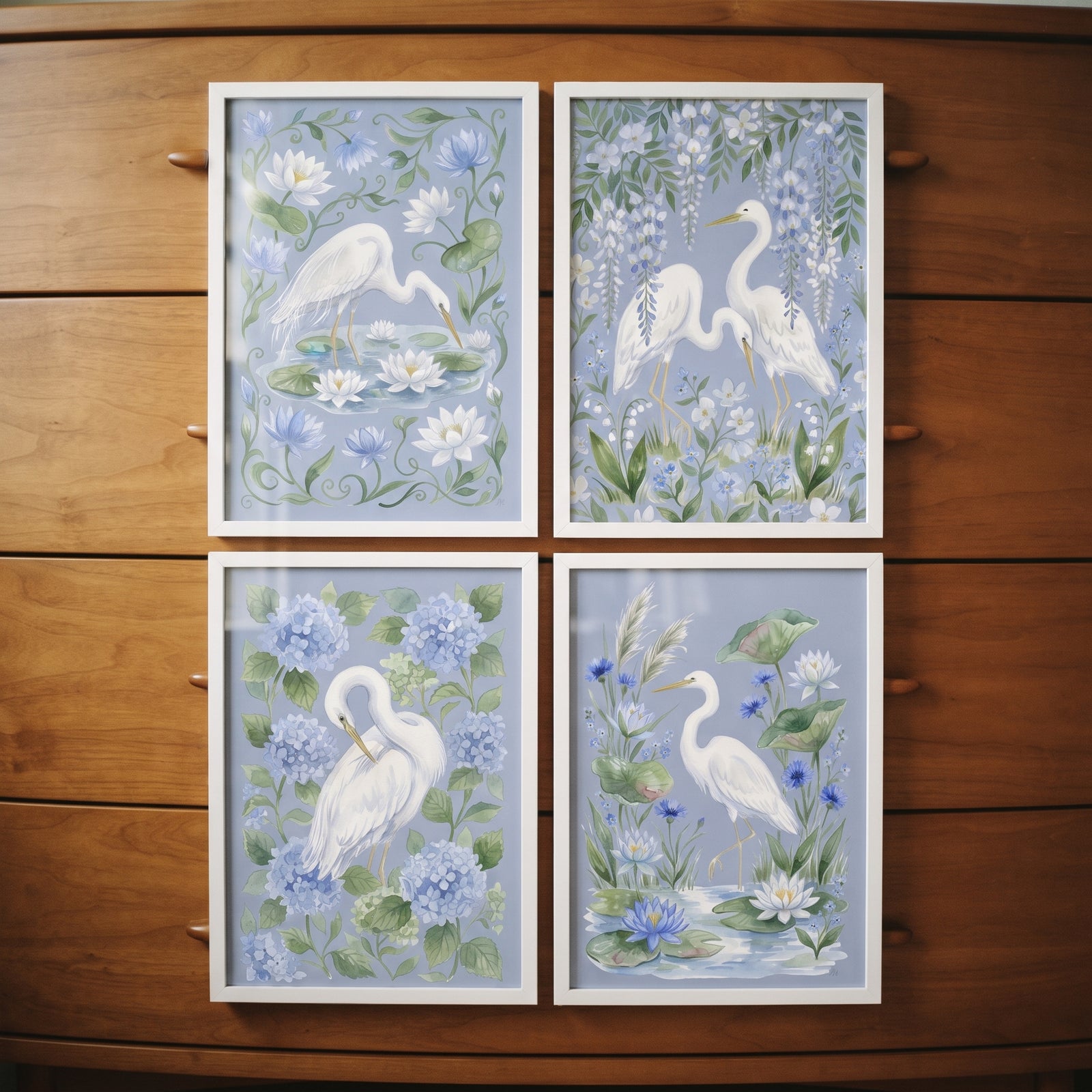 Chinoiserie botanical white heron bird wall art set of 4, featuring blue florals and white frames on a wood dresser.