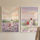 Two vertical white-framed illustrations hang on a light-colored wall. The illustration on the left shows Jesus in a long white robe walking through a field of purple lavender with a young girl in a red dress. He holds her hand while carrying a bouquet of white lilies behind his back. The illustration on the right depicts Jesus and the girl sitting on a wooden bench together in a field of light pink flowers. Both scenes feature soft, pastel skies and rolling hills in the background.