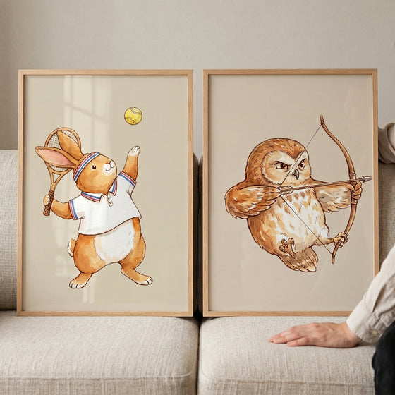 Classic storybook athletic animals wall art set of 2 with a rabbit playing tennis and an owl shooting a bow and arrow.