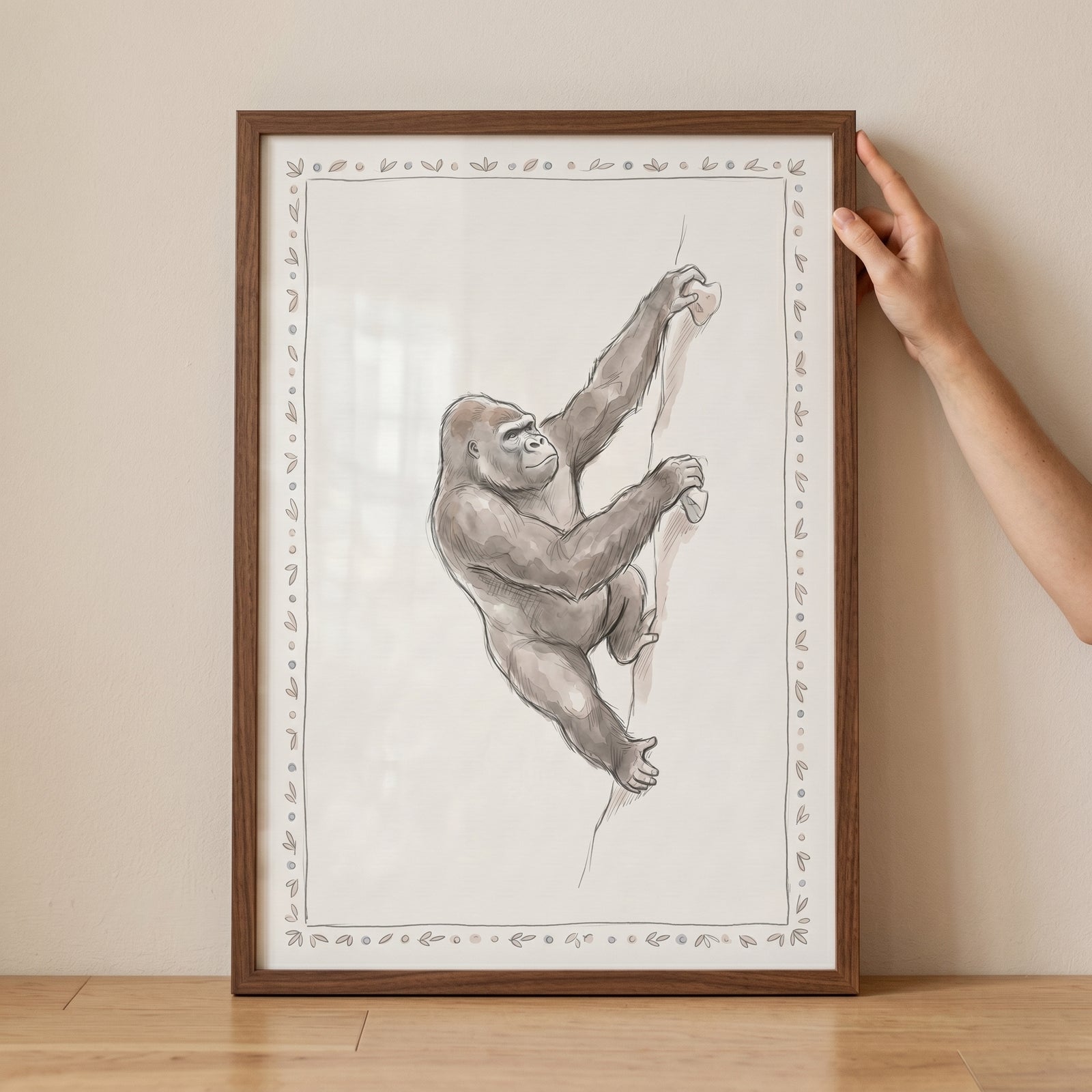 Framed sketch of a gorilla scaling a rock face, featuring a decorative border and climbing gorilla wall art.