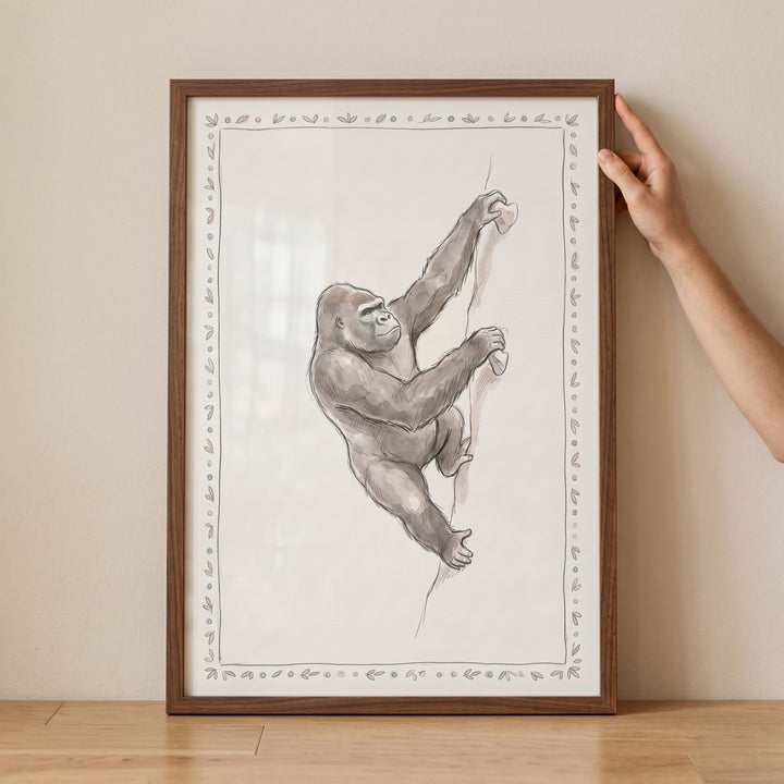 Framed sketch of a gorilla scaling a rock face, featuring a decorative border and climbing gorilla wall art.