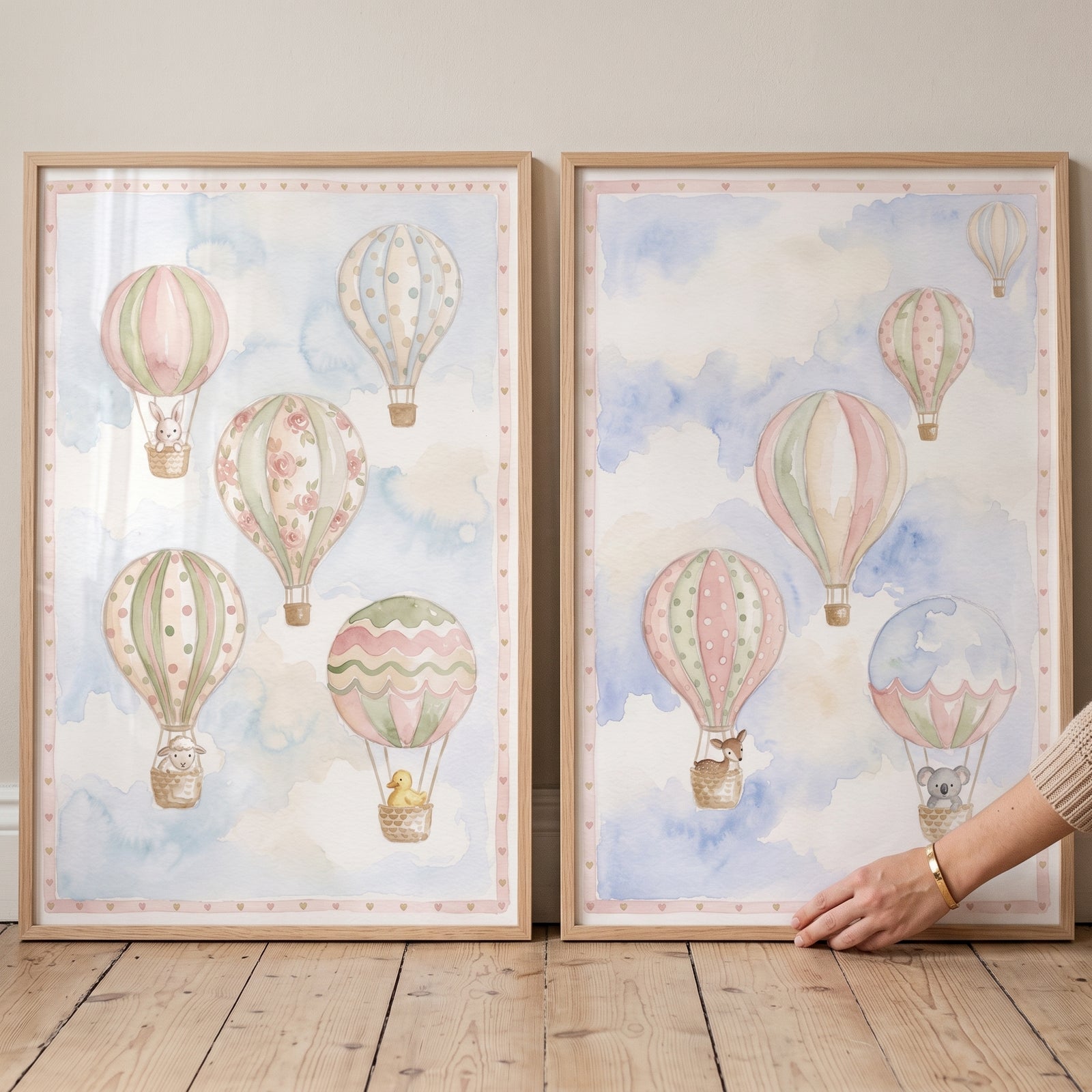 Pastel watercolor clouds hot air balloon wall art set of 2 with animals in baskets, framed in light wood on a floor.