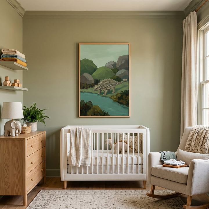Sage green nursery with a white crib, rocking chair, wooden dresser, and framed club tail dino wall art.